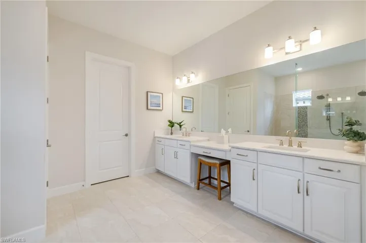 Full bath with double vanity, two vanities, a stall shower, and light tile patterned floors