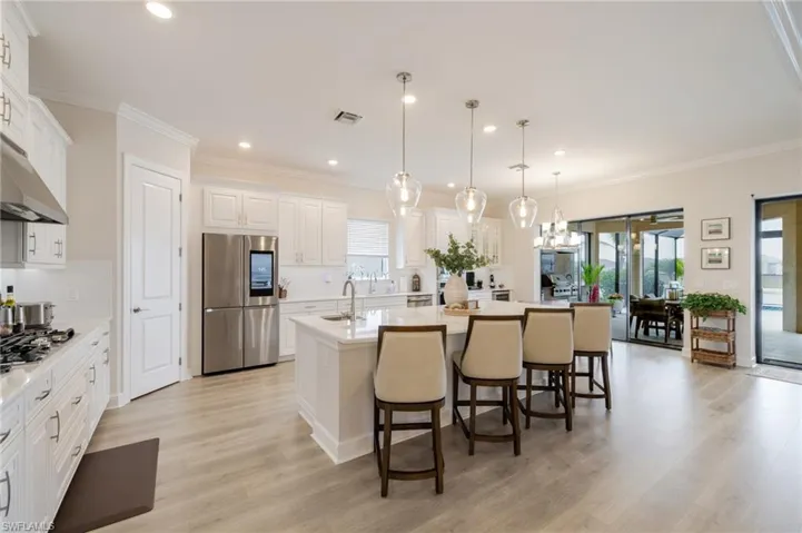 Kitchen featuring an island with sink, a kitchen breakfast bar, stainless steel appliances, white cabinets, and light wood-style flooring