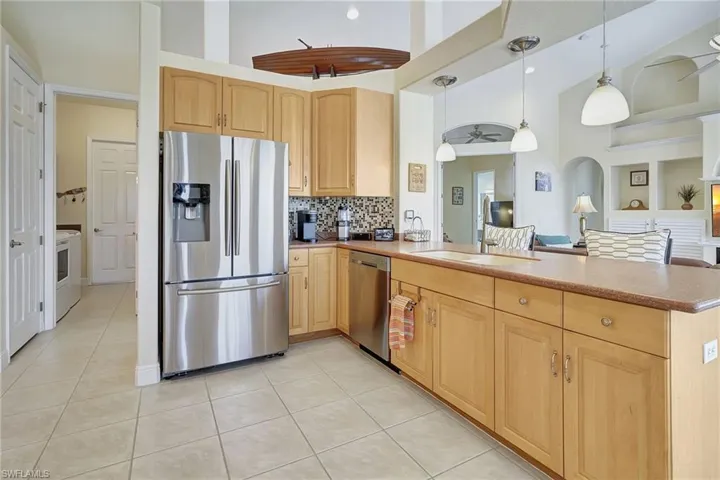 Kitchen featuring stainless steel appliances, kitchen peninsula, decorative backsplash, high vaulted ceiling, and ceiling fan