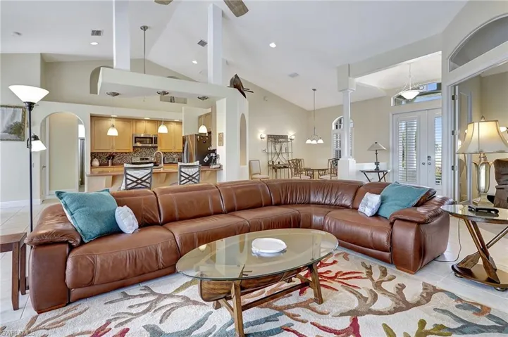 Tiled living room with ornate columns, french doors, and high vaulted ceiling