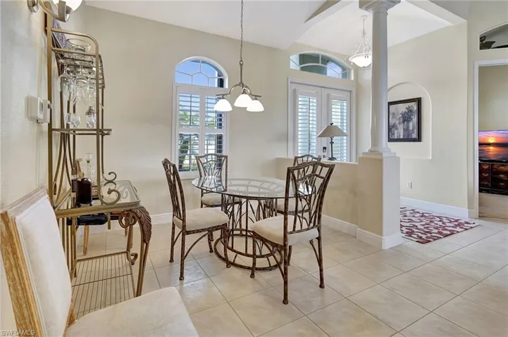 Tiled dining area featuring high vaulted ceiling and ornate columns