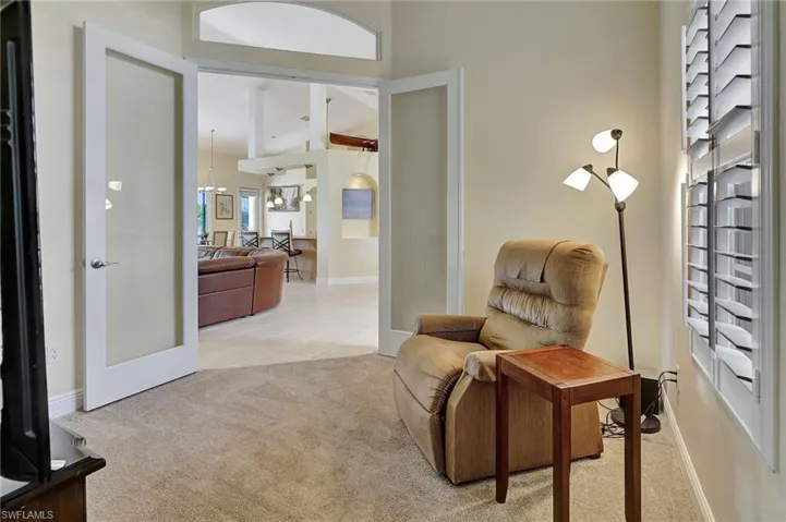 den with a high ceiling, french doors, and carpet flooring