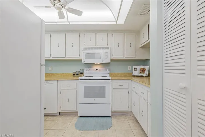 Kitchen with white cabinets, white appliances, and light tile patterned floors