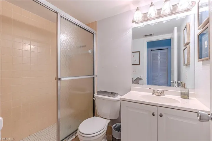 Bathroom with a shower with glass door, vanity, and toilet