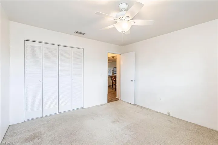 Unfurnished bedroom with light carpet, a closet, and ceiling fan