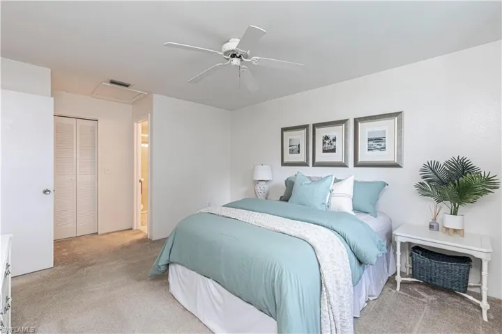 Bedroom featuring carpet flooring, connected bathroom, ceiling fan, and lots of storage in large closets.
