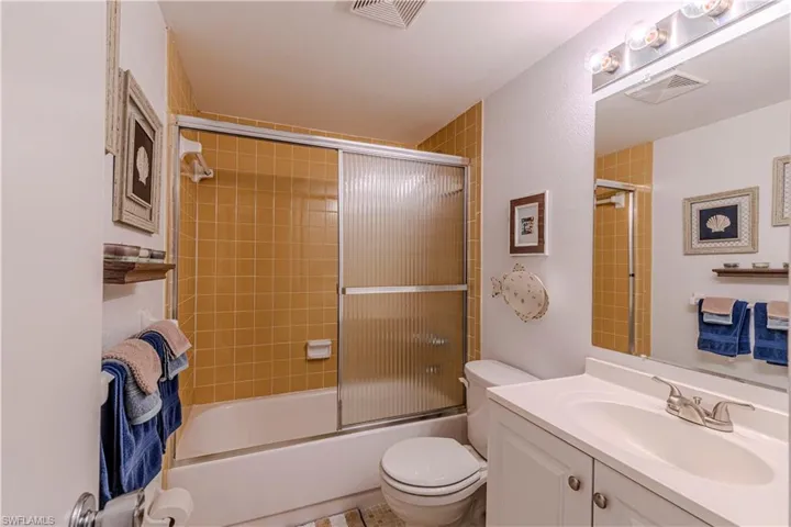 Full bathroom featuring vanity, combined bath / shower with glass door, and toilet