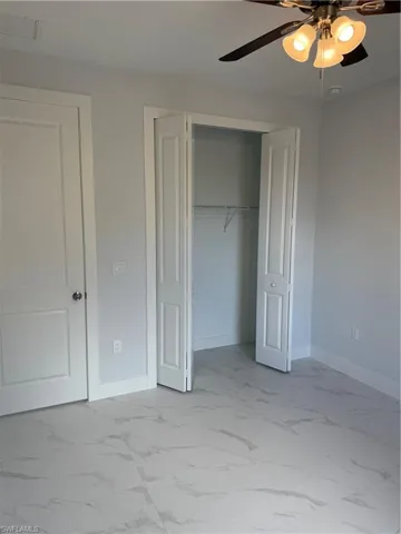 Unfurnished bedroom with ceiling fan and a closet