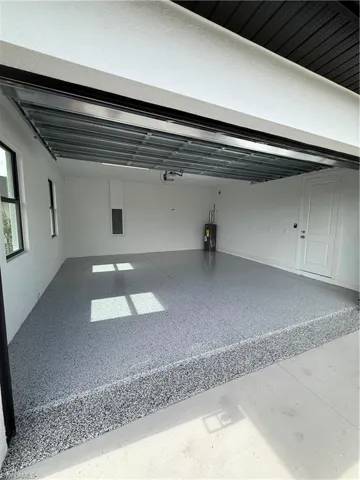 Garage featuring a garage door opener, electric panel, and water heater