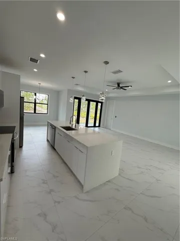 Kitchen with pendant lighting, sink, white cabinetry, and a spacious island