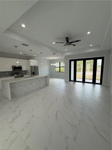 Unfurnished living room with sink, a raised ceiling, and ceiling fan
