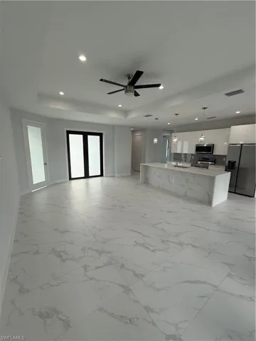 Unfurnished living room with ceiling fan and a raised ceiling