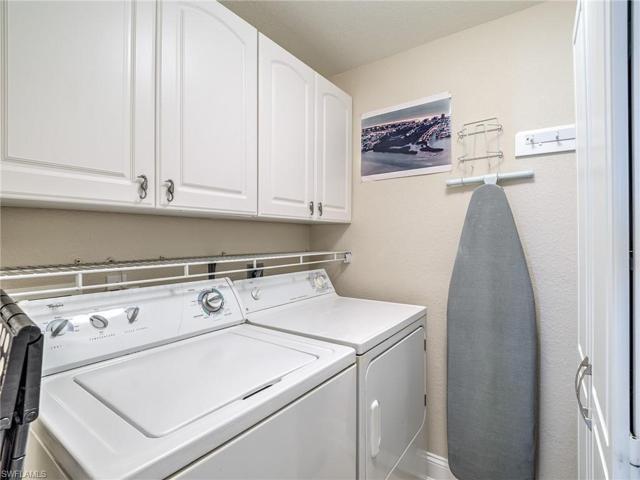 Walk-in laundry room with full size washer and dryer. Cabinets above plus upper and lower cabinet storage on opposite wall.