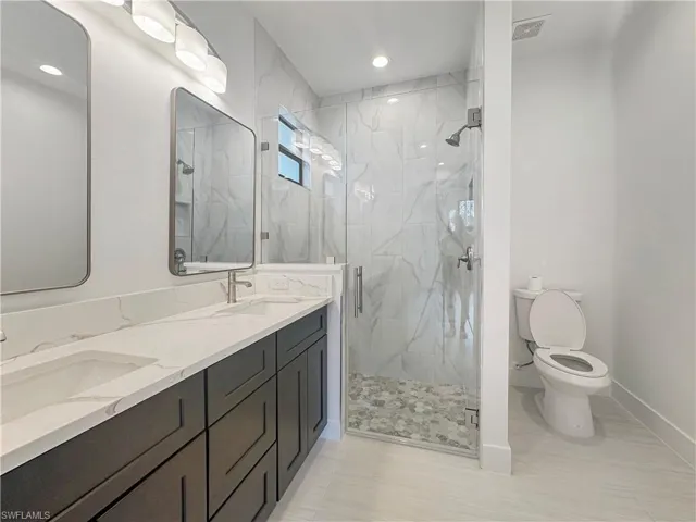 Bathroom with tile patterned flooring, an enclosed shower, toilet, and vanity
