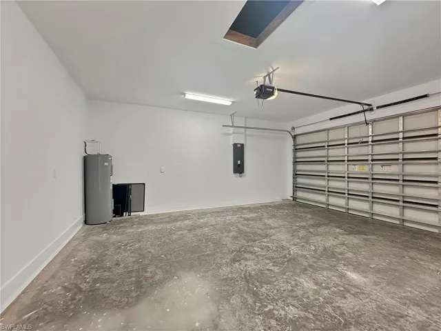 Garage with a garage door opener, water heater, and electric panel