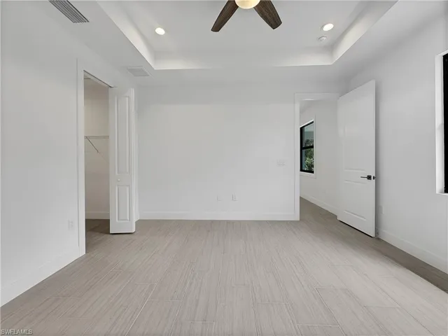Tiled spare room featuring ceiling fan and a raised ceiling