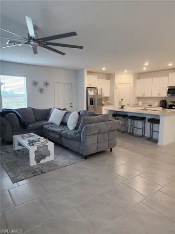 Living room featuring ceiling fan, light tile patterned floors, and recessed lighting