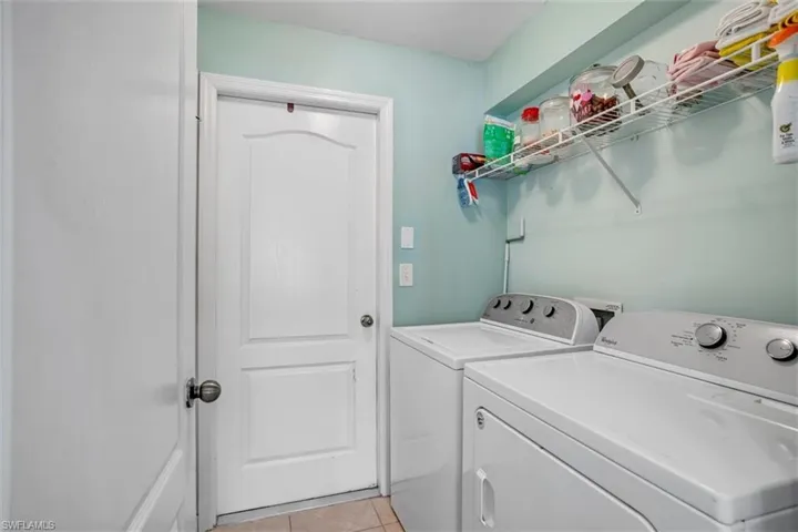 Washroom with washer and dryer and light tile flooring