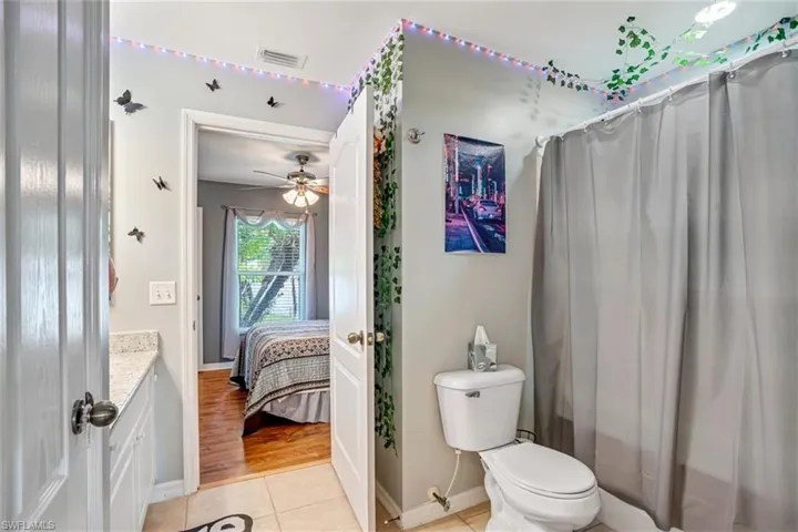 Bathroom featuring ceiling fan, vanity, toilet, and tile floors