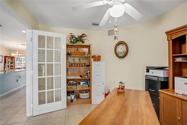 Tiled home office with ceiling fan with notable chandelier