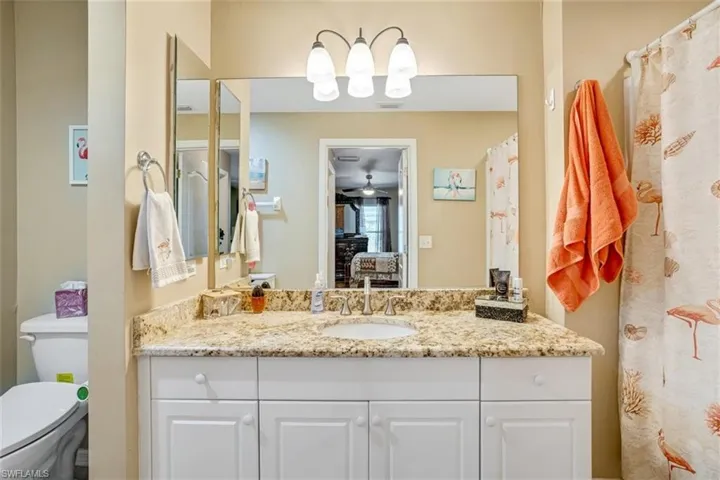 Bathroom featuring ceiling fan, vanity, and toilet
