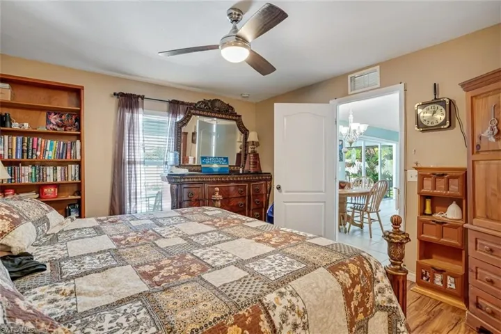 Bedroom with light hardwood / wood-style floors and ceiling fan with notable chandelier