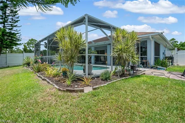 Back of house with a yard, glass enclosure, and a fenced in pool