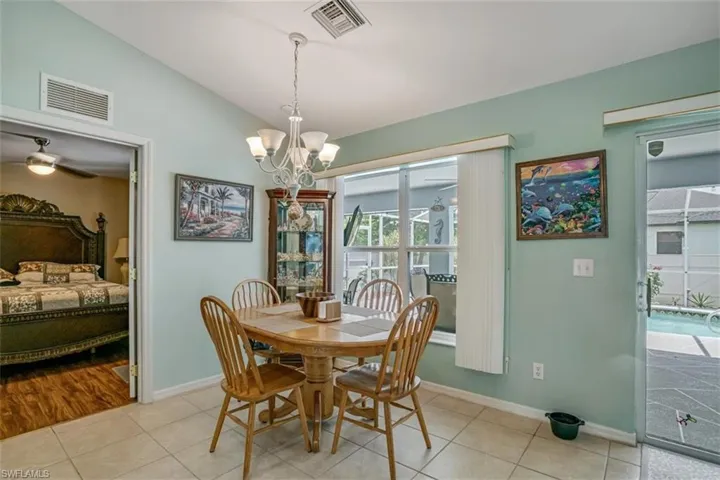 Tiled dining space featuring vaulted ceiling and ceiling fan with notable chandelier