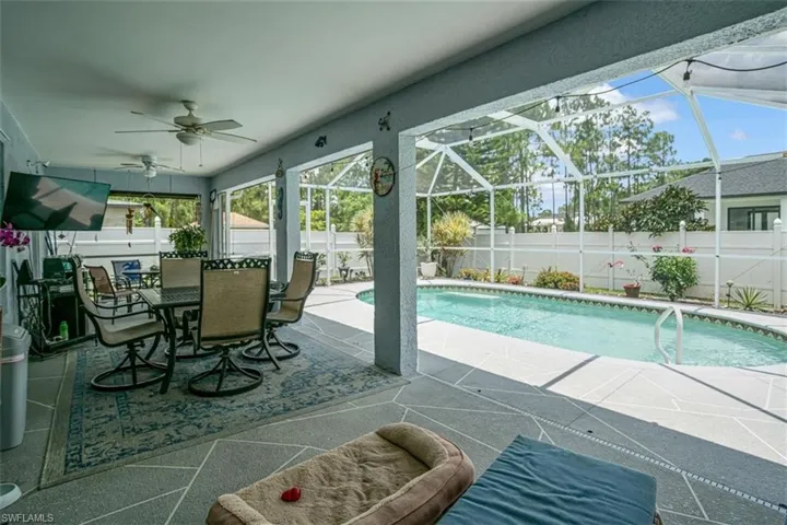View of pool with a patio, glass enclosure, and ceiling fan