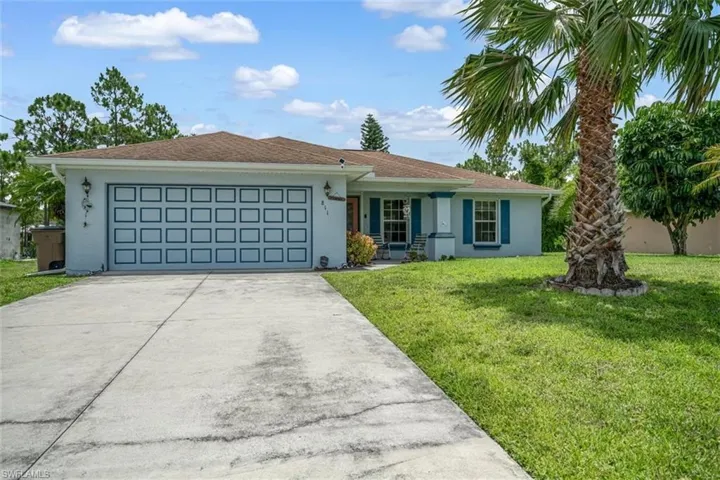 Ranch-style home featuring a garage and a front lawn