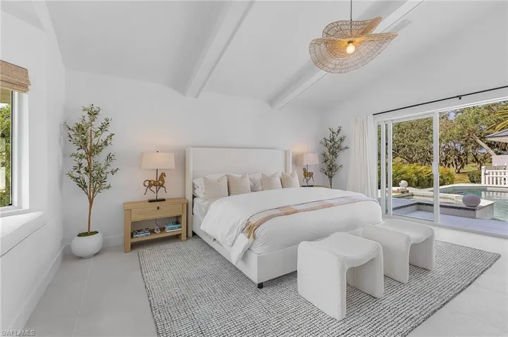Tiled bedroom featuring multiple windows, vaulted ceiling with beams, and access to outside