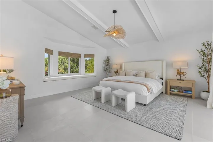 Tiled bedroom with beamed ceiling and high vaulted ceiling