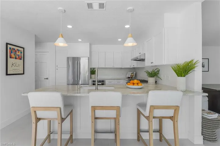 Kitchen featuring hanging light fixtures, light stone counters, high end refrigerator, and light tile floors