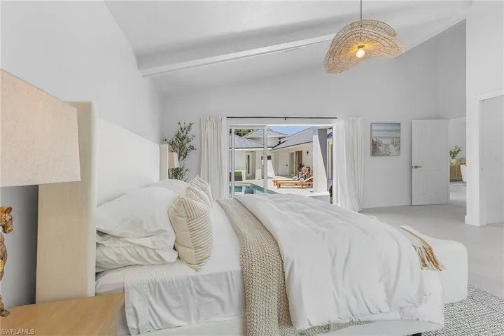 Tiled bedroom featuring access to outside and vaulted ceiling with beams
