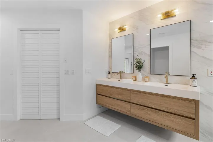 Bathroom with tile floors, double sink vanity, and tile walls