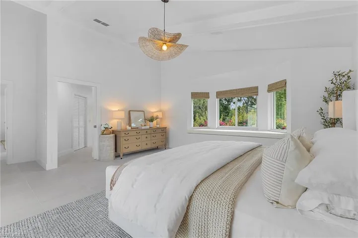 Bedroom with beamed ceiling, high vaulted ceiling, and light tile floors