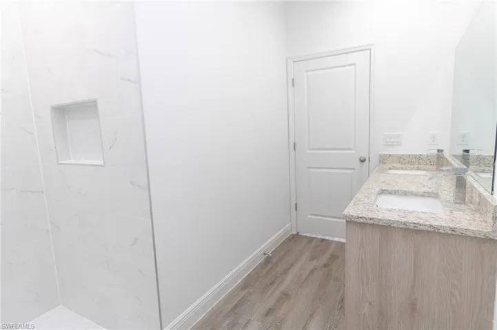 Master bathroom featuring a sink, double vanity, wood finished floors, and baseboards