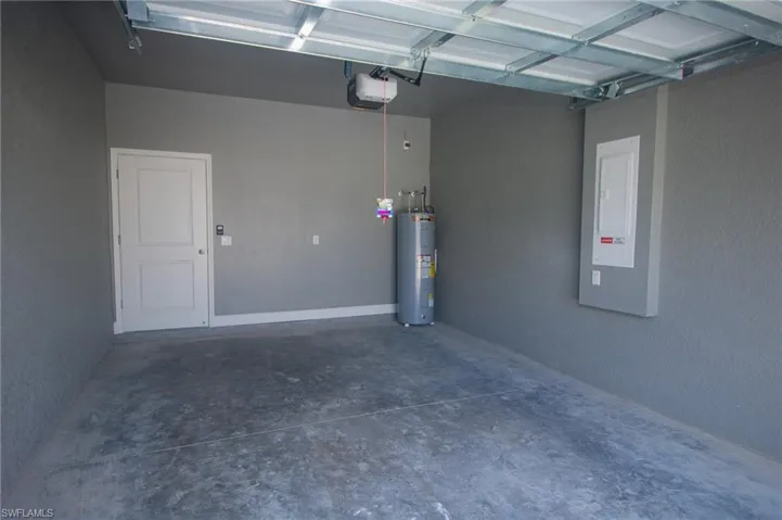 Garage featuring a garage door opener, electric panel, and water heater