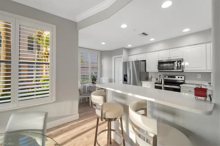 Kitchen with white cabinetry, a breakfast bar, appliances with stainless steel finishes, a peninsula, and light wood finished floors