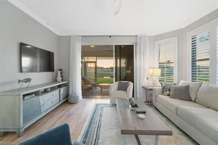 Living room featuring light wood-style flooring, ornamental molding, and ceiling fan
