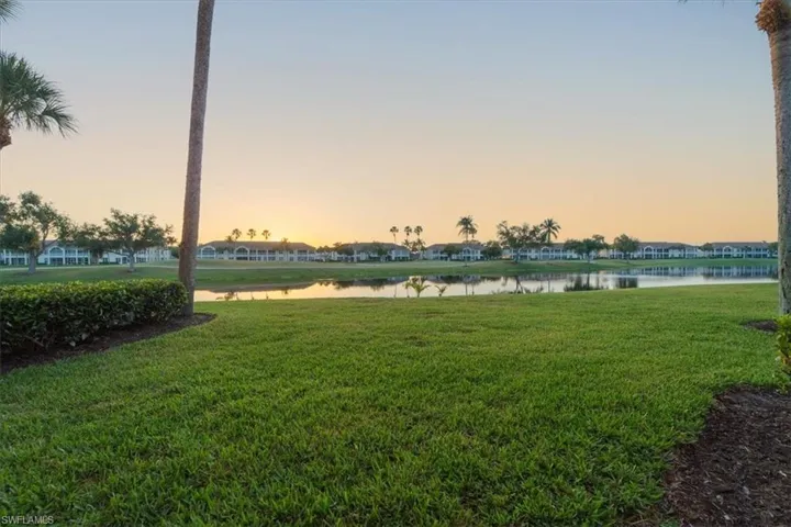 Yard at dusk with a water view and a lawn