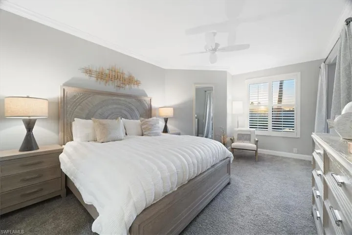 Bedroom with dark colored carpet, crown molding, and ceiling fan