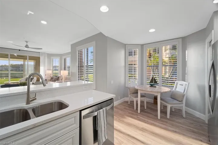 Kitchen with light stone counters, appliances with stainless steel finishes, light wood-style flooring, recessed lighting, and plenty of natural light