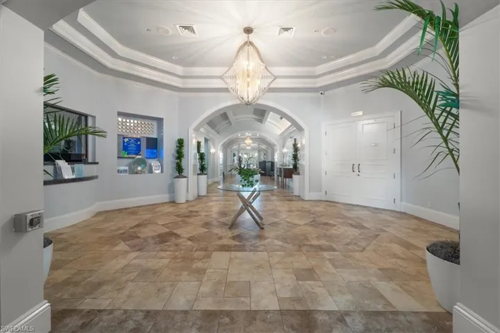 Entryway with arched walkways, a chandelier, ornamental molding, and a tray ceiling