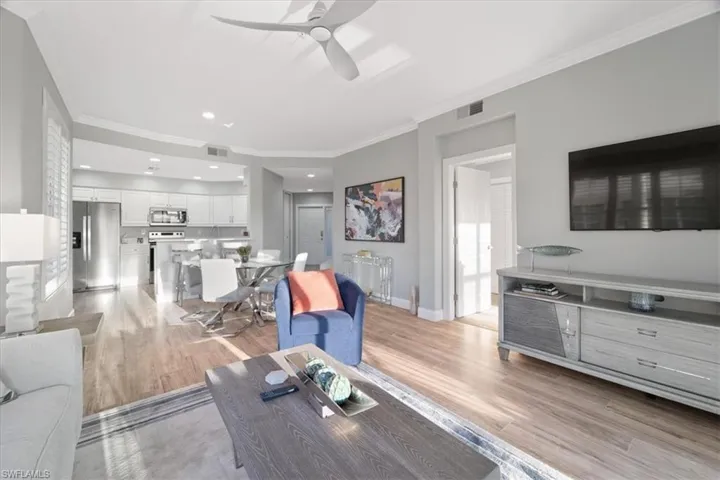 Living room featuring ceiling fan, crown molding, light wood-style flooring, and recessed lighting