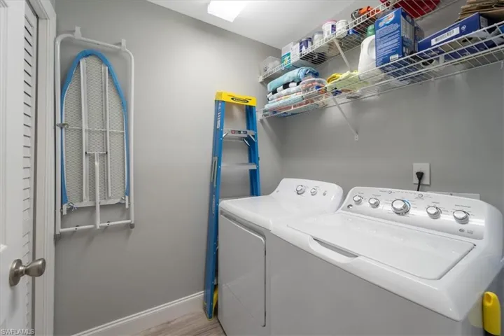 Laundry room with washer and clothes dryer and light wood finished floors