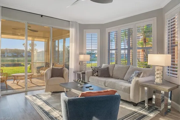 Sunroom with wood finished floors, a water view, and ornamental molding