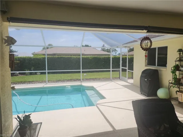 View of swimming pool with enclosed lanai under truss