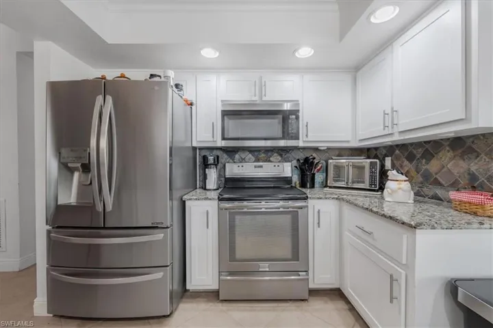 Kitchen featuring stainless steel appliances, white cabinets, tasteful backsplash, and recessed lighting