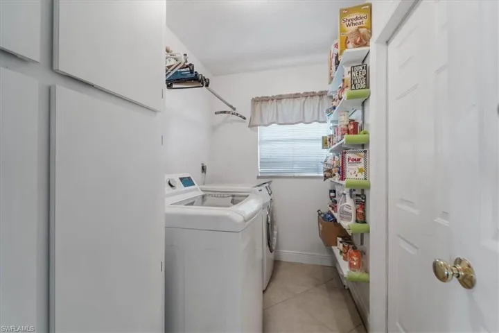 Laundry area featuring independent washer and dryer and light tile patterned flooring